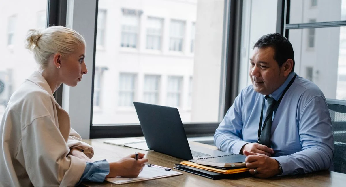 Ethnic boss asking question to female candidate filling information form on clipboard during hiring meeting
