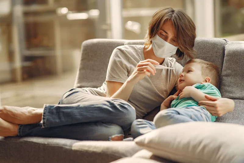 Mère prenant la température de son enfant à la maison