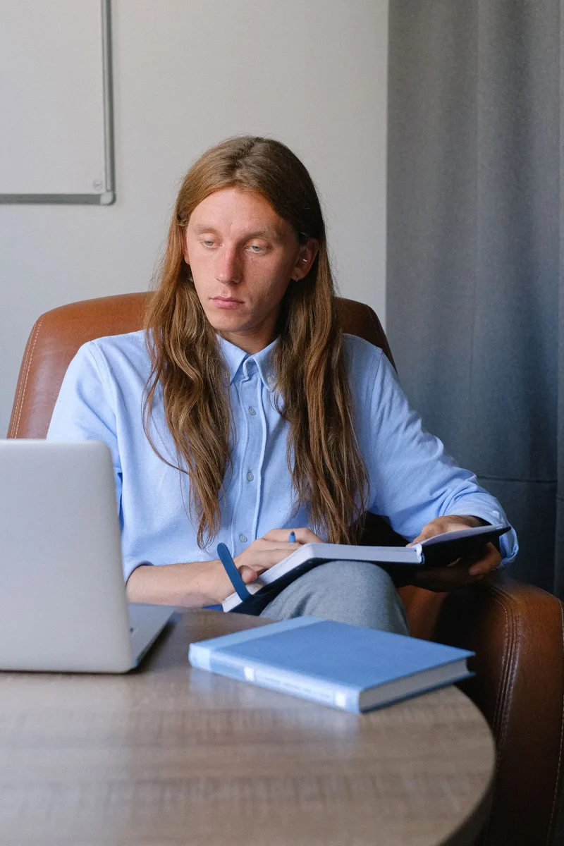 Professionnel consultant un carnet près de son ordinateur portable