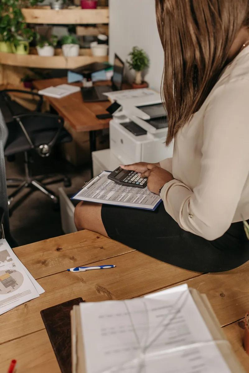 Professionnelle utilisant une calculatrice pour examiner un dossier