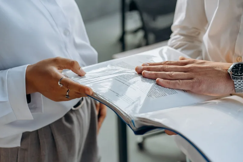2 personnes examinant ensemble un document posé sur une table